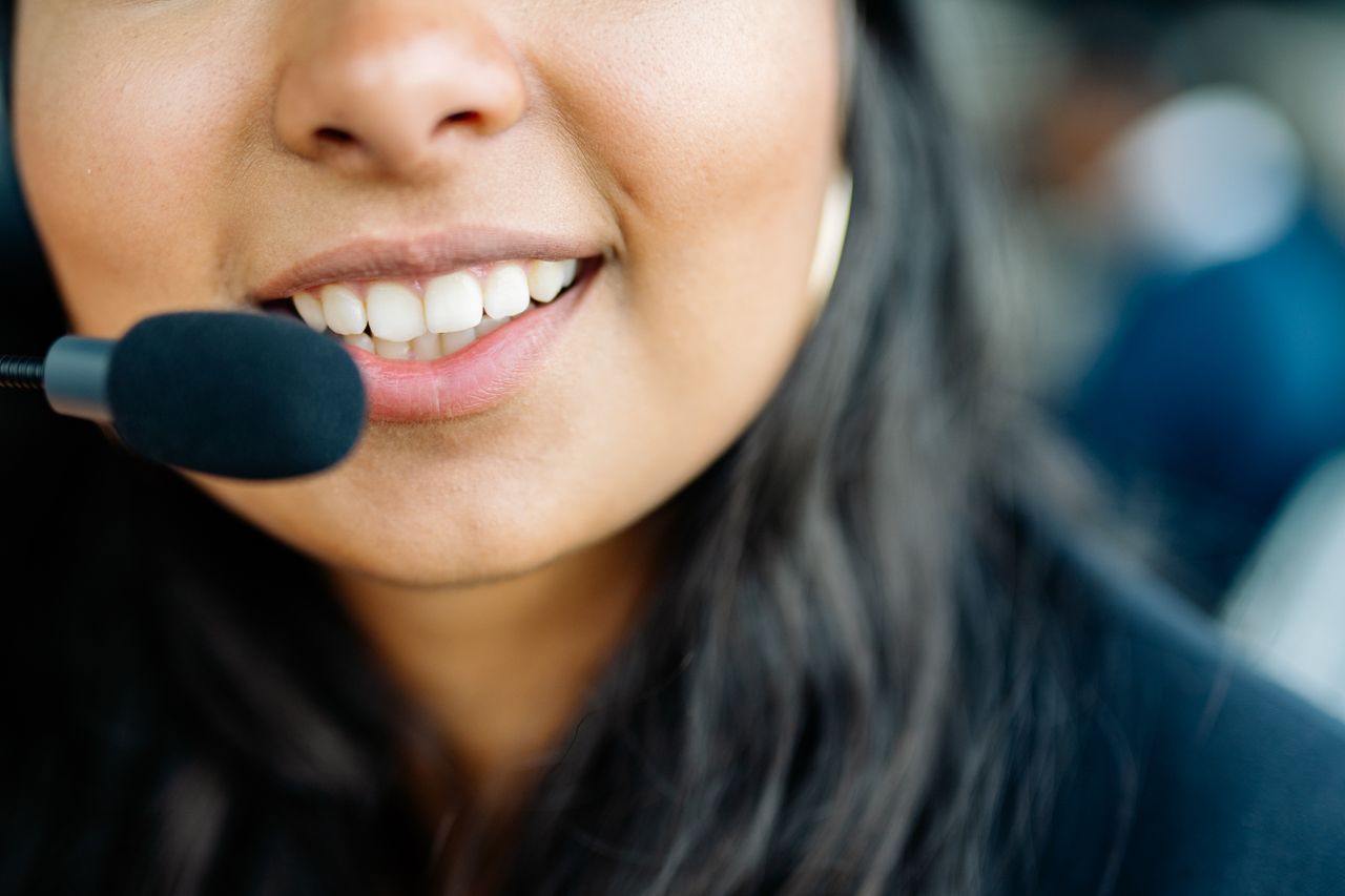 services-01 Close-up of a smiling customer service agent wearing a headset in an office environment.